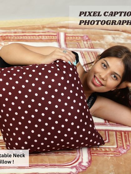 A model posing with a maroon polka-dot cushion, showing its size and soft texture.