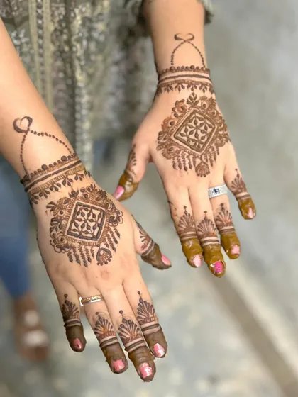 A chic and modern design for the back of the hands. This style features a geometric pattern that resembles a piece of jewelry, with a delicate chain connecting to the finger.
