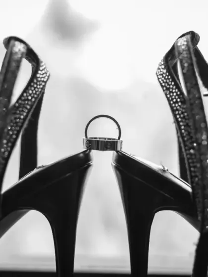 An artistic black and white shot of the wedding ring balanced perfectly between the bride's heels. It's a stylish and creative way to photograph the wedding details.