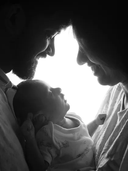 Sometimes, the most powerful emotions are conveyed in black and white. This silhouette-style portrait of new parents and their baby uses dramatic lighting to create a timeless and intimate family photograph that focuses purely on their connection.