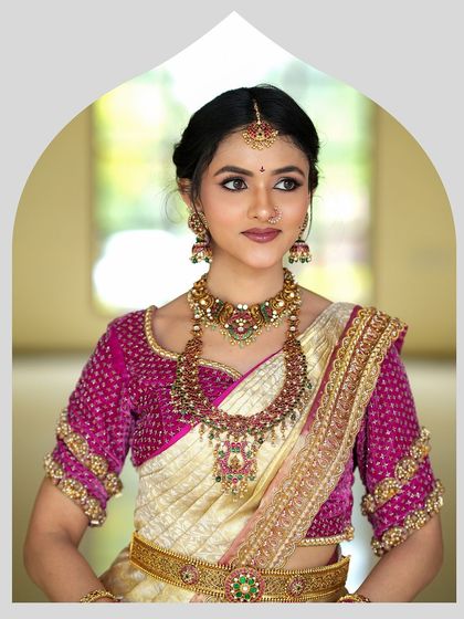 A portrait of elegance, this bride wears a custom magenta blouse with her traditional silk saree. The intricate detailing on the blouse sleeves adds a layer of luxury.