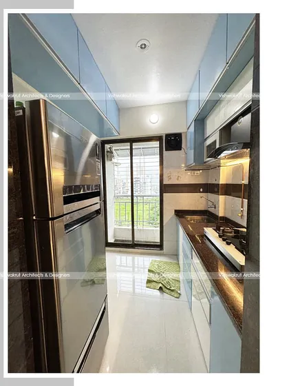 A view of the 1BHK modular kitchen, showing the placement of the refrigerator and the seamless integration of appliances into the design.