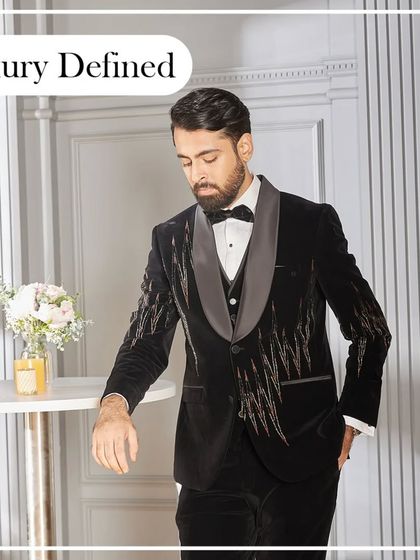 Luxury defined. A model leans casually in the black and gold embroidered velvet tuxedo, showcasing its effortless style and sophisticated edge.