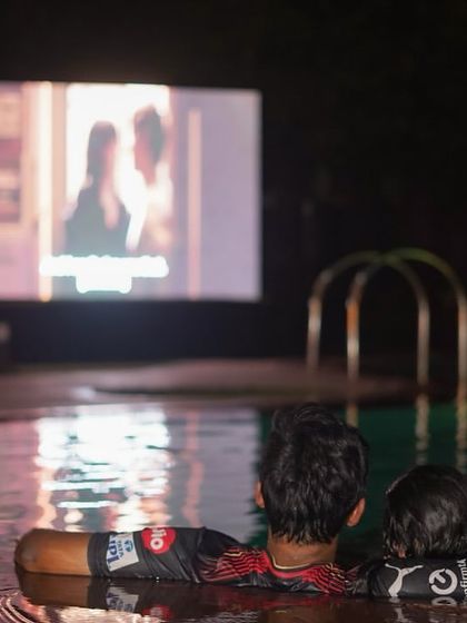 A couple enjoying a romantic movie from the edge of the pool. Our Dive-in Cinema offers a unique and intimate setting for a date night.
