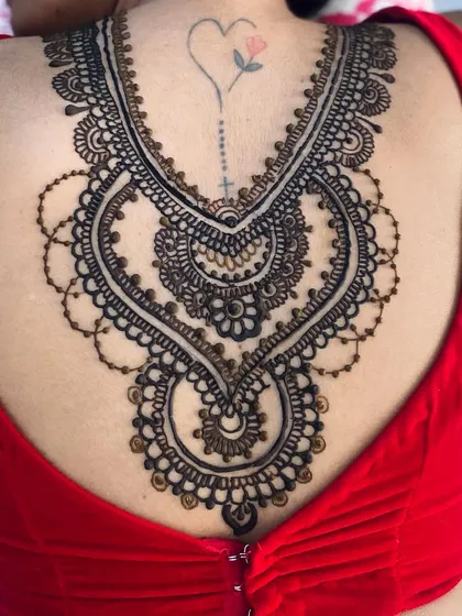 My artistry isn't just for hands and feet. This stunning henna piece, designed like an intricate necklace, beautifully adorns the client's back, making a unique and elegant statement for a special occasion.