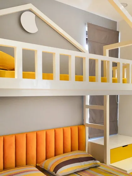 A custom-designed bunk bed with a house-frame top bunk, creating a fun, fort-like space for sleeping. The bright orange headboard adds a vibrant pop of color.