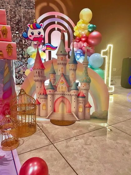 Another view of the unicorn castle prop, showing how it integrates with the neon '1' sign and balloon clusters to create a magical photo corner.