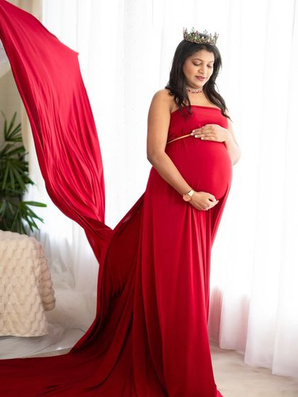 A powerful portrait using a flowing red satin fabric against a bright window. The fabric toss adds movement and drama, creating a silhouette that is both strong and beautiful.