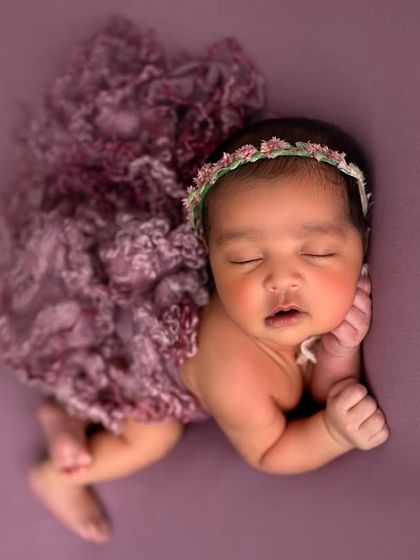This little button looks so angelic with her rosy cheeks and a delicate floral headband. The textured purple wrap adds a lovely pop of color.