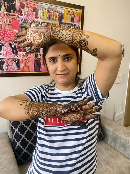 A playful pose from a happy mom-to-be, displaying her detailed maternity henna. The design is a beautiful way to adorn and celebrate her baby bump.