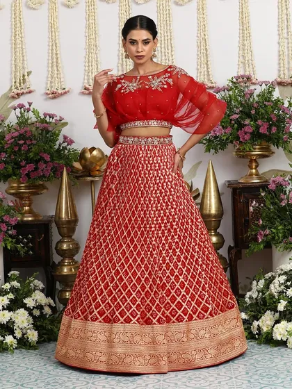 This red Bandhani embroidered lehenga with a golden zari border is a true showstopper. The contemporary organza cape blouse adds a modern, fashionable twist.