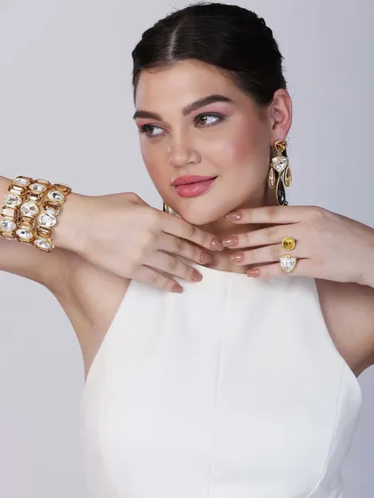 A close-up shot where the model's hands frame her chin, highlighting the ring and bracelet. This intimate framing is effective for beauty and accessory campaigns.