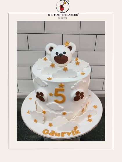 A sweet and simple teddy bear cake for Gaurvik's 5th birthday. The design features a cute bear peeking out from fluffy buttercream clouds and golden stars, making it an adorable choice for a young child.