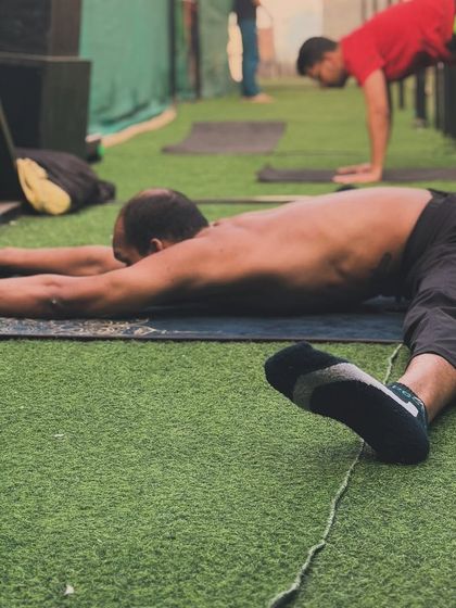 An athlete works on a half-split variation (Ardha Hanumanasana), intensely stretching the hamstring of the front leg while opening the hip of the back leg.