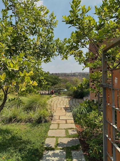 A stone pathway meanders through a lush garden filled with native grasses and fruit trees. This entrance sequence was designed to feel like a natural trail, immediately immersing visitors in a biodiverse environment.