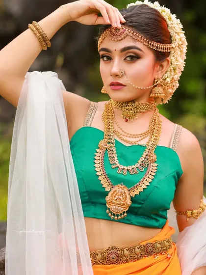 A Bahubali-inspired "Sakhi" look, featuring a unique drape and antique jewelry, set against a lush green backdrop for an epic, cinematic feel.