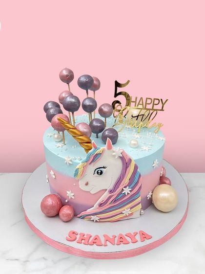A magical unicorn cake for Shanaya's 5th birthday, featuring a pastel rainbow mane and a cascade of candy-like spheres.