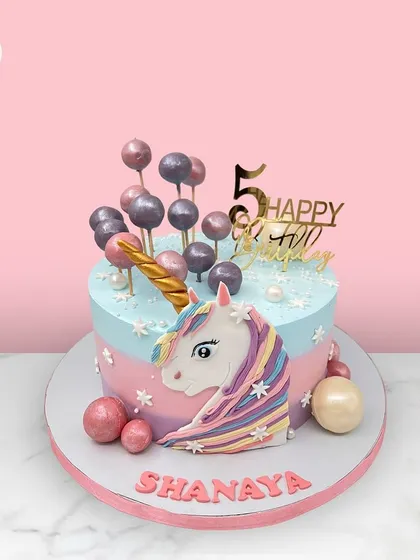 A magical unicorn cake for Shanaya's 5th birthday, featuring a pastel rainbow mane and a cascade of candy-like spheres.