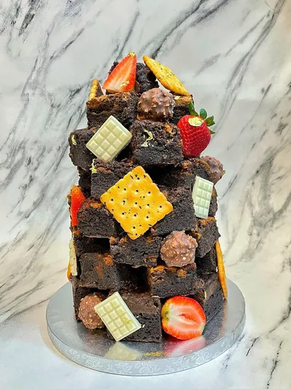 This is my signature Lotus Biscoff brownie stack, a unique alternative to a traditional birthday cake. It's a tower of rich, fudgy brownies decorated with fresh strawberries, white chocolate, and crunchy biscuits, perfect for any brownie lover.