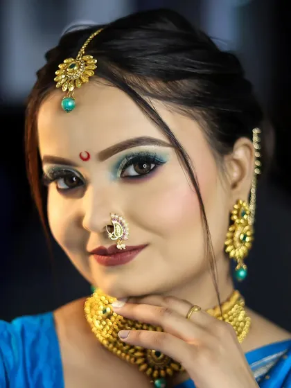 A smiling portrait of the model, showcasing the beautiful gold jewelry and the red bindi.