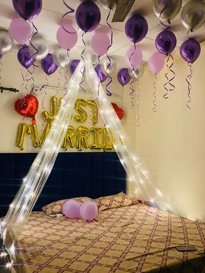 A clear shot of the "Just Married" foil balloons in gold, contrasting beautifully with the purple and silver color scheme of this wedding night setup.
