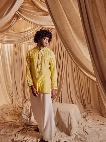 A full-length shot of a groom in traditional attire. The makeup and grooming are subtle, enhancing his natural features and ensuring he looks sharp and well-presented for his wedding ceremonies.