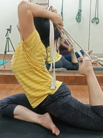 A student masters Rajakapotasana (King Pigeon Pose) with the help of a yoga belt. The belt helps to bridge the gap and deepen the backbend while maintaining proper form.