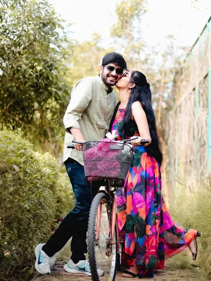 A playful and affectionate shot of a couple with a bicycle on a garden path. This candid moment perfectly captures the joy of their relationship.