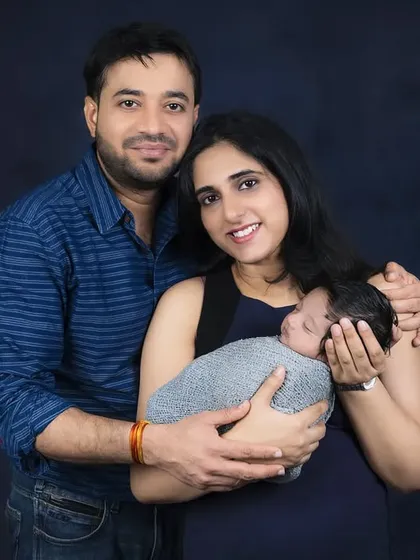 A first family portrait with a newborn, captured in a dramatic fine-art style. The dark background creates an intimate feel for this special moment.