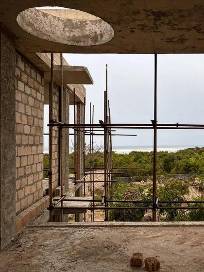 A view from an unfinished room at Kizikula, looking out towards the sea. The circular oculus in the ceiling slab is a design feature that will bring a focused beam of daylight into the space below.