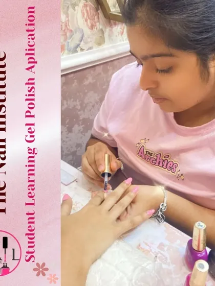 A student carefully applies a coat of pink gel polish, practicing her technique for a smooth and professional application.