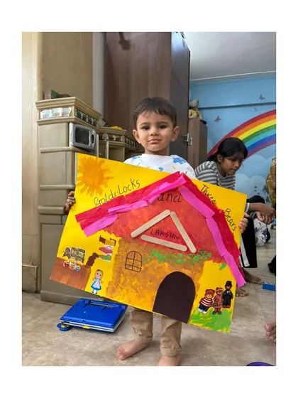 This young artist proudly displays the bear's cottage he created, complete with a popsicle stick roof.