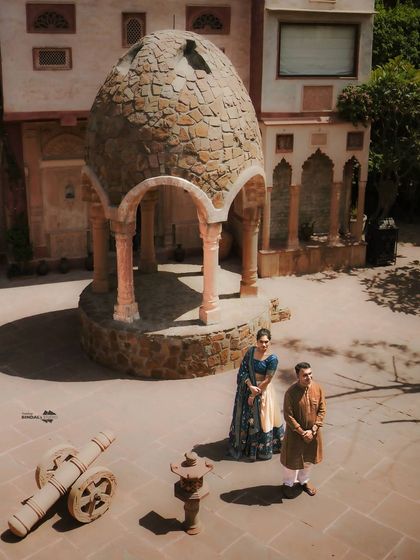 An aerial view of the couple in a stone courtyard, emphasizing the scale and beauty of the heritage venue. This angle provides a unique, cinematic perspective on their pre-wedding story.