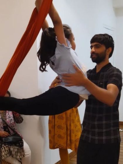 I believe in making yoga fun for kids. Here, I'm assisting a young student in an aerial pose, helping her feel safe and confident.