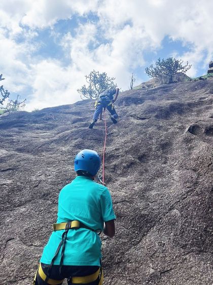 A view from the belayer's perspective as a climber ascends the rock face.