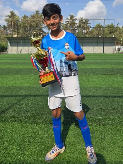 Pointing to the trophy, this U14 player celebrates his team's success.
