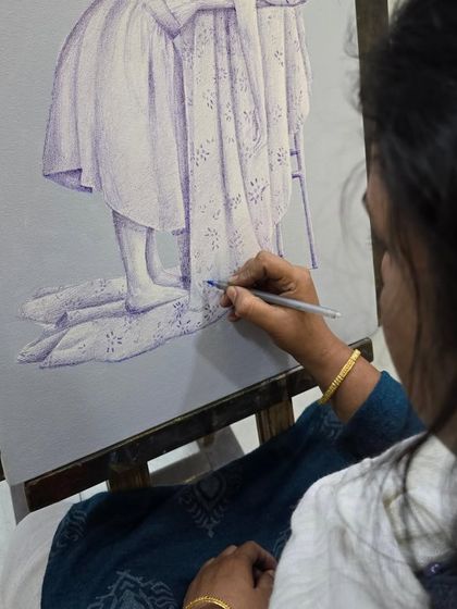 This image captures a student working on the delicate fabric details of her surreal ballpoint pen drawing, using fine lines to create texture.