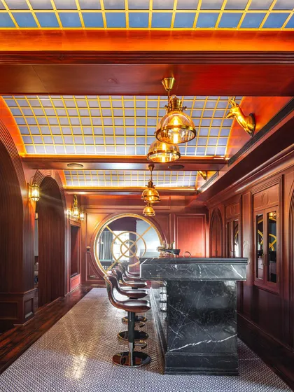 The Irish-style bar at the Wanderlust Villa, featuring rich red wood, a stained-glass ceiling, and classic bar stools. It's a space designed to transport you to another place and time.