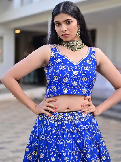 A powerful pose showing off the full outfit. The makeup is strong and confident, designed to make a statement on the runway.