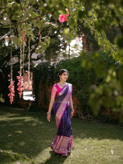 A bride walking through a garden, her beautiful saree flowing around her.