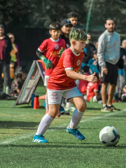 A young player with dyed green hair dribbles the ball with confidence during the Pride Cup finals.