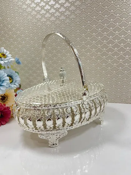 The elegant silhouette of our oval silver basket with its handle up. The intricate legs and detailed patterns make it a standout piece for any special occasion.