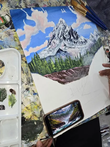 See the process come to life. Here, a student works on a detailed acrylic landscape, learning to layer colors and build depth by referencing a photograph, with all the necessary materials at their fingertips.
