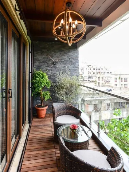 This design combines natural textures for a sophisticated look. I used dark wood deck flooring, a slate stone accent wall, and a comfortable wicker bistro set, all brought together by a statement rope chandelier for evening ambiance.