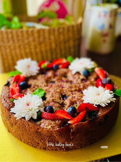 A close-up of my strawberry and blueberry crumble cake, decorated with fresh flowers. It’s as beautiful as it is delicious.