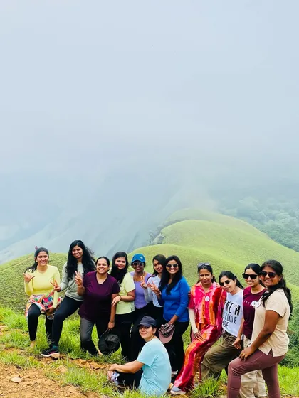 A group of women posing on the Netravati trail, with the iconic green ridge disappearing into the clouds.