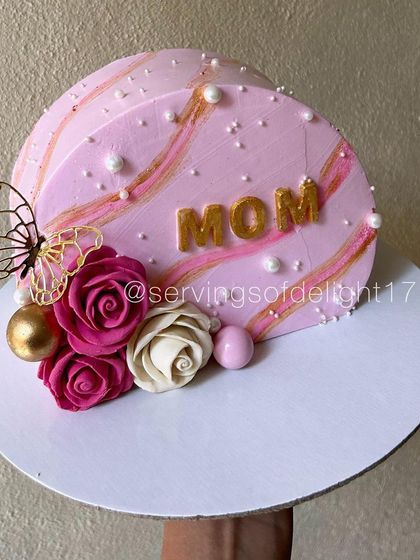 A close-up of the modern pink cake for Mom, showing the detail in the floral arrangement and the gold lettering.