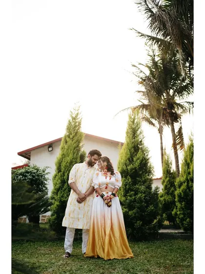 A full-length portrait of the couple in their stylish Haldi outfits. The natural outdoor setting and their loving glance make for a beautiful pre-wedding photograph.