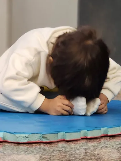 A candid shot of a toddler deeply focused on a stretch. These moments of quiet concentration are just as important as the high-energy dance moves.