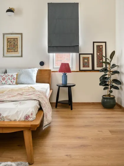 This bedroom in 'House of Kismish' has a Modern Indian vibe, with a simple wooden bed frame and a low ledge for displaying art.